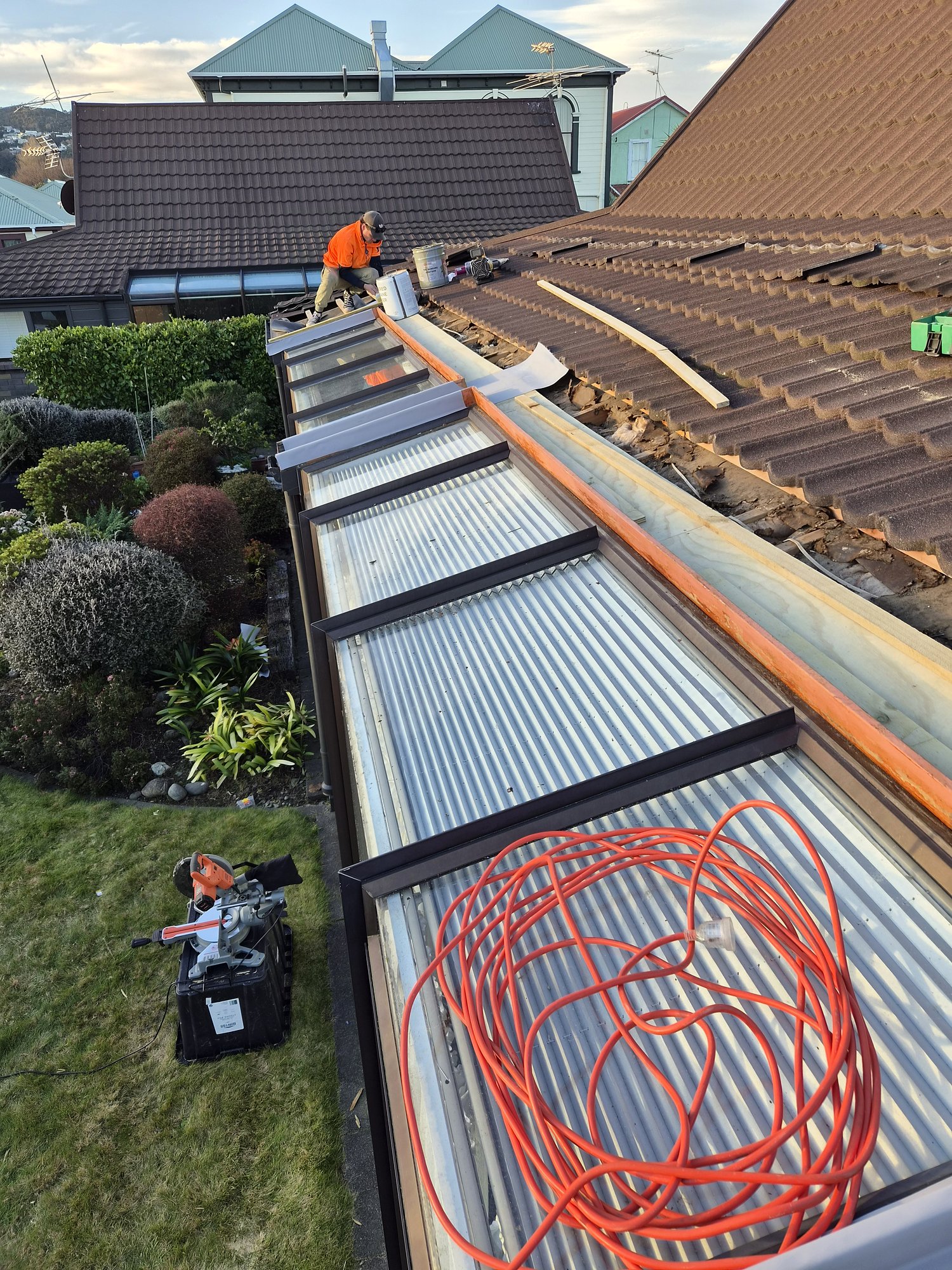 New long-run corrugated roof sheets and gutter beside an older tile roof
