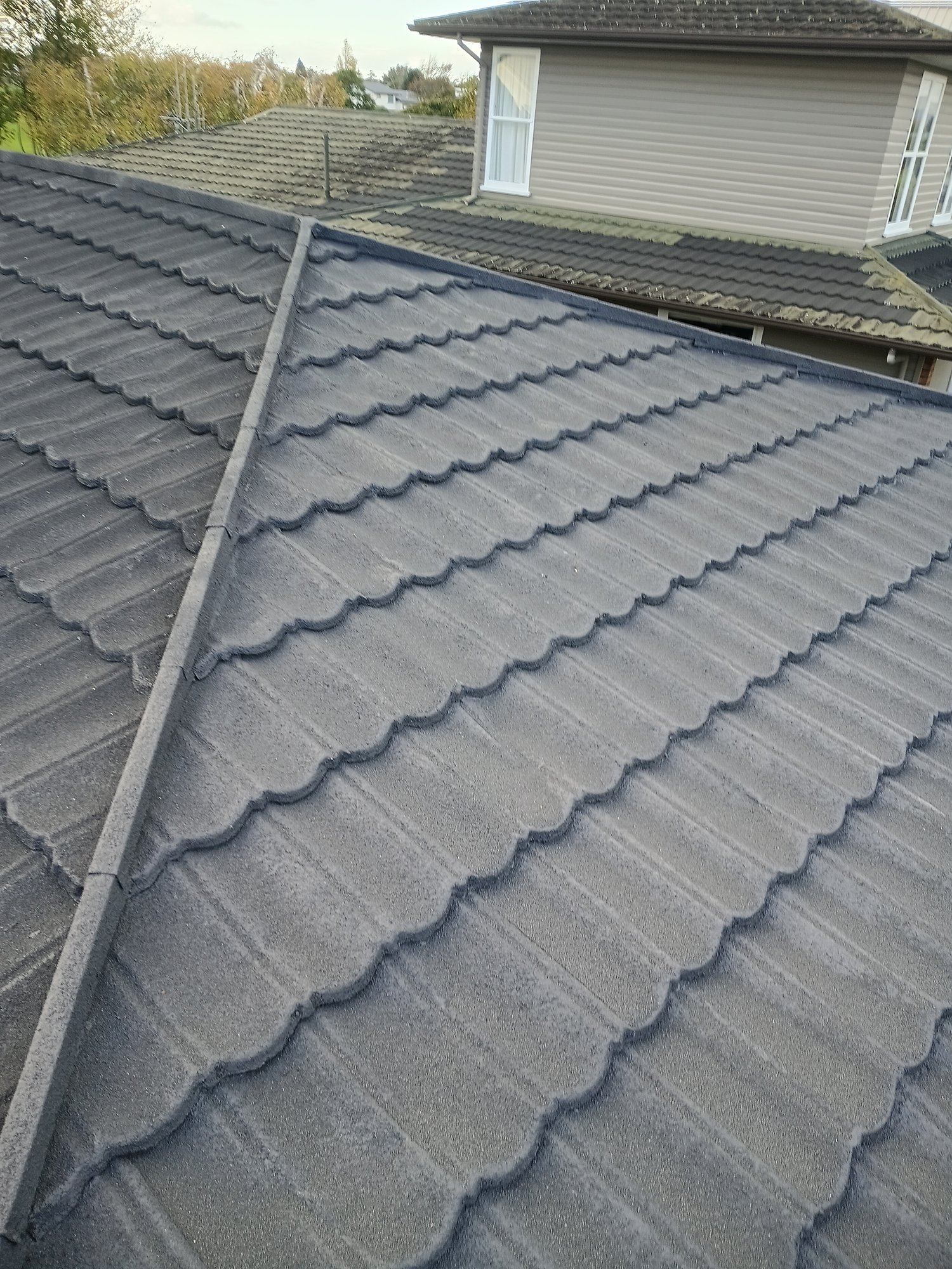 Close-up of a profiled concrete tile roof with ridge capping and gutter